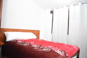 a bedroom with a bed with a red blanket and a window at Hotel GUERRERO in Zacatlán