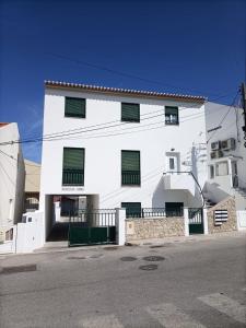 a white building with black windows on a street at Diana's House - Nazaré in Nazaré
