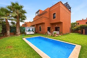 a villa with a swimming pool in front of a house at Villa des Roses in Marrakesh
