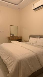 a bedroom with a white bed and a mirror at شقة واسعة وانيقة in Hail