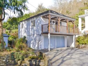 a blue house with a balcony and a garage at River Lodge in Polperro +1 photo