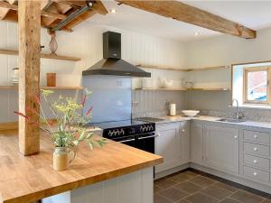 a kitchen with white cabinets and a black stove top oven at The Granary in Oxborough +18 photos