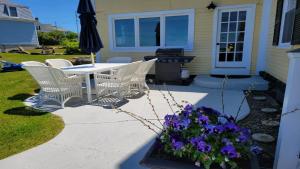 a patio with white chairs and a table and purple flowers at Oceanfront Classic Maine Cottage In Close Walking Distance To Beaches! in York