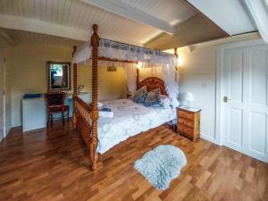 a bedroom with a canopy bed and a wooden floor at 2 The Folly's - Uk45188 in Abbotskerswell
