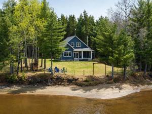 a blue house on the shore of a body of water at Riverside Retreat in Rexton