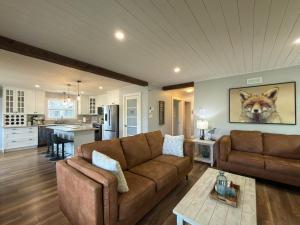 a living room with a brown couch and a kitchen at Riverside Retreat in Rexton