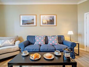 a living room with a blue couch and a coffee table at High Dougarie Farmhouse in Dougarie