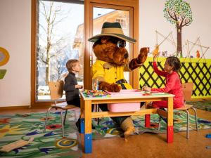 a stuffed bear sitting at a table with two children at Landal Brandnertal in Bürserberg