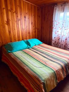 a bed in a room with a wooden wall at Casa familiar Queule in Queule