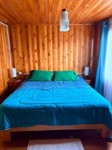 a bedroom with a blue bed with wooden walls at Casa familiar Queule in Queule