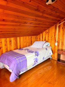 a bedroom with a bed in a wooden room at Casa familiar Queule in Queule