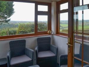 a porch with two chairs and windows with a view at The Stables in Dunterton