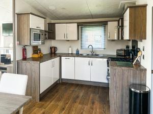 a kitchen with white cabinets and a wooden floor at Toucana - Uk49468 in Morpeth