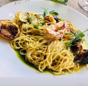 a white plate of pasta with shrimp and vegetables at Elite Gold Luxury Hotel in Abuja