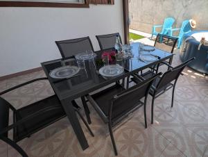 a black table with chairs and plates and flowers on it at La Casa Créole, spa, 3 ch, 2 sdb, centre de la Guadeloupe in Les Abymes