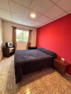 a bedroom with a bed and a red wall at Aires de Mendoza in Maipú +6 photos