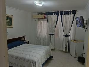 a bedroom with a bed and two windows with curtains at Hotel Lord by Croma in Cúcuta