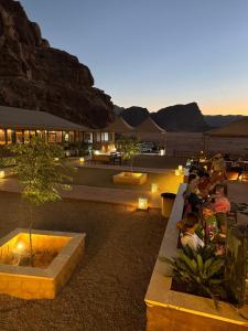 a group of people sitting on benches in the desert at MARTIAN LANDSCAPE lUXURY CAMP in Wadi Rum