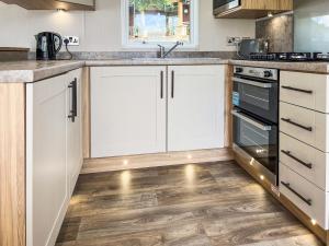a kitchen with white cabinets and a wooden floor at Drover's Den - Uk50090 in Durham