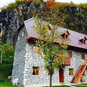 un gran edificio de piedra con techo rojo en Bujtina Berishta Theth, en Theth