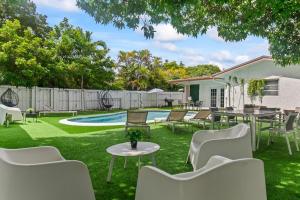 a yard with chairs and a table and a pool at New Casa Eva Turfed Pool 5Br in Hallandale Beach