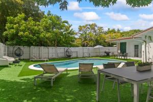 a backyard with a pool and a table and chairs at New Casa Eva Turfed Pool 5Br in Hallandale Beach
