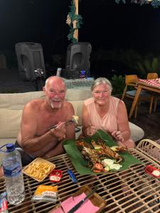 a man and woman sitting at a table with a plate of food at Three Queen Villa and Homestay in Waikabubak