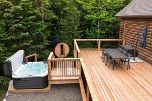 a wooden deck with a hot tub and a table at Fiddler Lake Resort - Rabbit 57 in Mille-Isles
