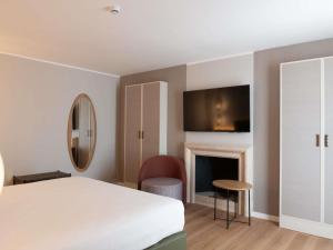 a bedroom with a white bed and a fireplace at Mövenpick Hotel Bari in Bari +128 photos