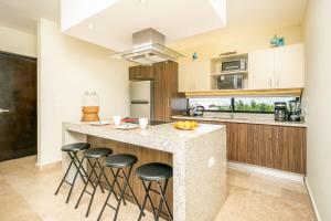 a kitchen with a island with bar stools at 2Br Condo W Rooftop Pool & Backyard in Playa del Carmen