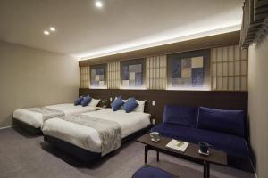 a hotel room with two beds and a couch at KURASHIKI Station HOTEL 和奏 in Kurashiki