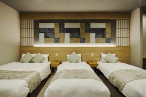 a room with three beds and a painting on the wall at KURASHIKI Station HOTEL 和奏 in Kurashiki