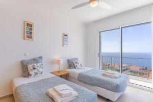 a bedroom with two beds and a large window at Villa Eldomar Heated Pool in Estreito da Calheta +39 photos