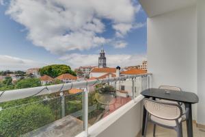 ein Balkon mit Tisch und Stühlen und Blick auf eine Stadt in der Unterkunft Sunflower Ocean View Apartment With Pool & Parking in Caniço
