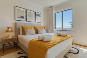 ein Schlafzimmer mit einem großen Bett und einem großen Fenster in der Unterkunft Sunflower Ocean View Apartment With Pool & Parking in Caniço