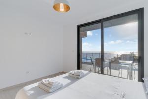 a bedroom with a white bed with a view of the ocean at Casa Mozart Ii Sea View, Pool & Sunny Retreat in Estreito da Calheta +27 photos