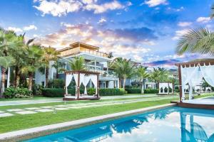 a mansion with a swimming pool and palm trees at Sublimeluxcondo Terrenas Jaccuzibeachfront in Las Terrenas