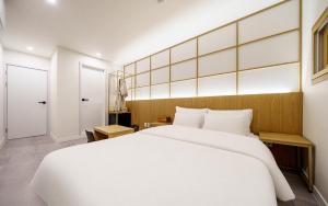 a bedroom with a large white bed and a door at Ryokan Hotel The Red Dragonfly in Incheon