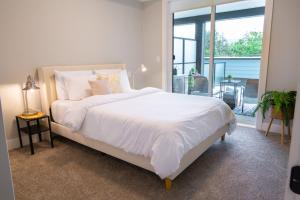 a bedroom with a large white bed and a balcony at New 1 Bed Condo with Mtn Views in Harrison Hot Springs