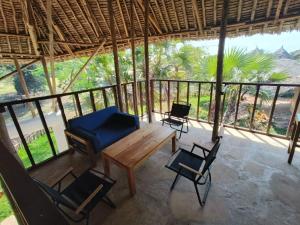 a porch with chairs and a wooden table at Seasoul Sanctuary in Shimoni