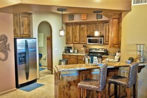 a kitchen with wooden cabinets and a stainless steel refrigerator at Bella Sirena 305-A - Elegant Oceanview Condo on Beachfront Resort in Puerto Peñasco