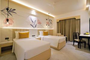 a hotel room with two beds and a desk at Hotel Le Jardin in Erode