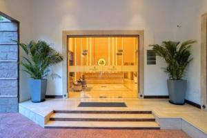 a lobby with two potted plants in front of a door at Hotel Le Jardin in Erode +67 photos