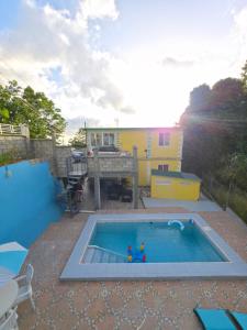 a swimming pool in front of a yellow house at Barefoot Apartments in Roseau