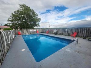 a swimming pool with red chairs next to a fence at Trailsman Lodge in Baddeck