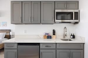 a kitchen with gray cabinets and a sink and a microwave at Beachside Maui studio with pool & hot tub access in Wailea