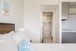 a white bedroom with a bed and a kitchen at Beachside Maui studio with pool & hot tub access in Wailea