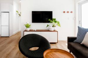 a living room with a black ottoman in front of a tv at Quiet Central Home Near Newlands Cricket in Cape Town