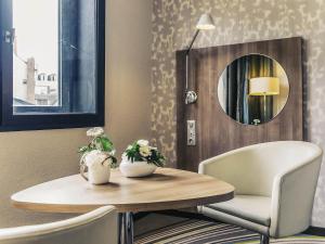 ein Tisch, ein Stuhl und ein Spiegel in der Unterkunft Mercure Angers Centre de Congrès in Angers