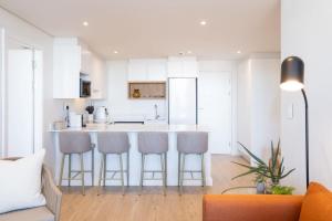 a kitchen with white cabinets and a bar with stools at Newlands Peak Luxury Suite in Cape Town